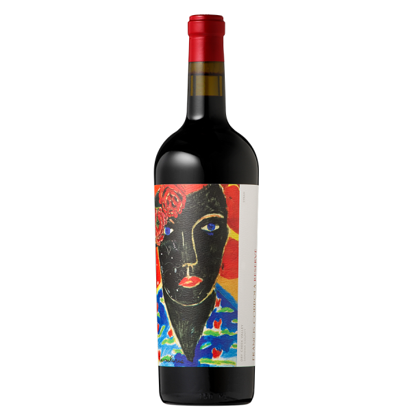 A wine bottle with a vibrant abstract label featuring a person's face in black with bright blue eyes and red lips, against a red and blue background.