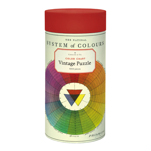 Vintage cylindrical puzzle box with a red lid, labeled "Color Chart Vintage Puzzle." Features a colorful circular chart and text, evoking a retro feel.