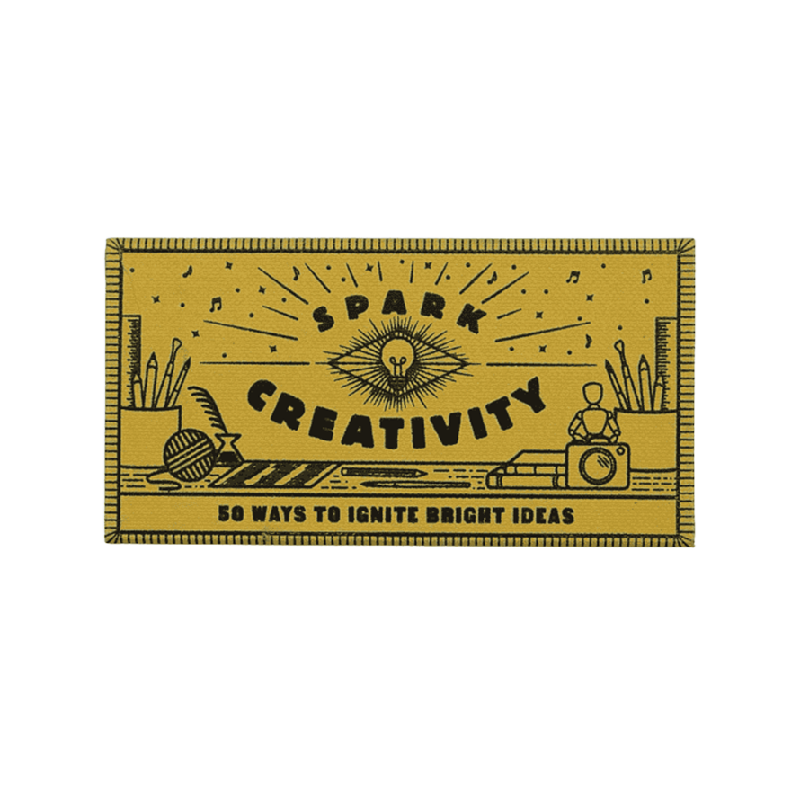 Yellow matchbox with black text "Spark Gratitude" and illustrations of a sun, open book, plant, and teacup. Text reads "50 Ways to Appreciate Every Day."