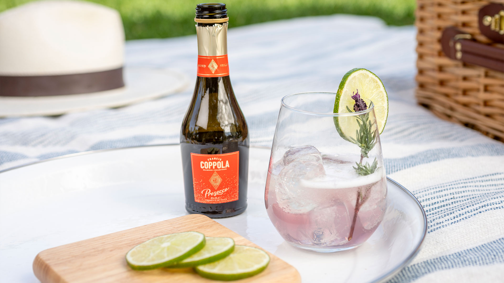 A mini bottle of Diamond Collection Prosecco next to a lavender lime spritz cocktail in a picnic style setting